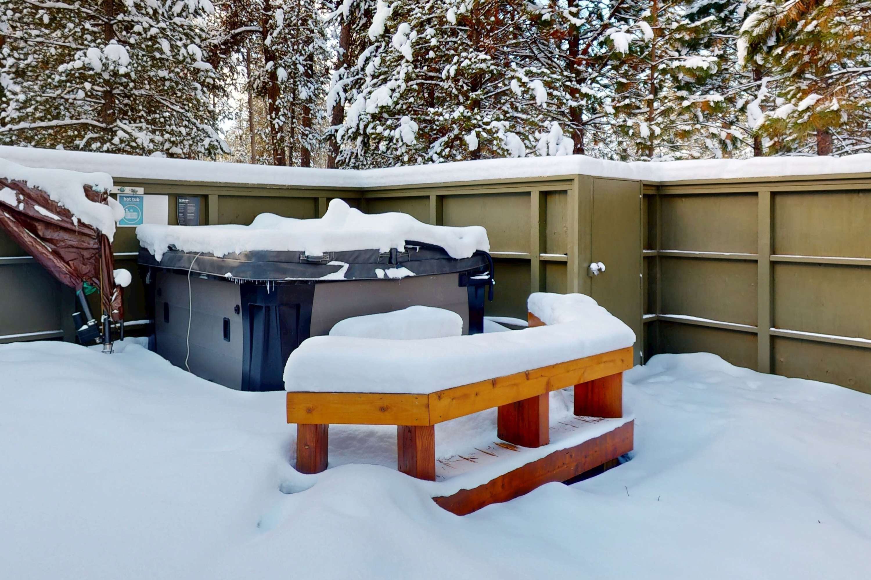 A snow-covered outdoor area with a wooden bench and a hot tub.