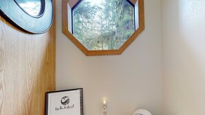 Un letrero de bienvenida enmarco, una ventana de madera con vistas a un bosque y un enchufe en la pared.