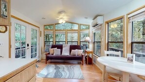 Una sala de estar acogedora con un sofá, una mesa de comedor y ventanas grandes.