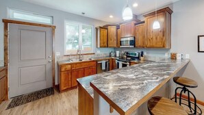 Una cocina con armarios de madera, encimera de granito, microondas y un lavabo.