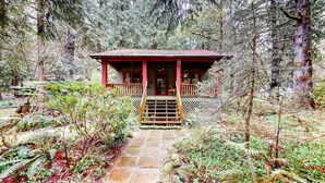 Una cabana amb un porxo, envoltada per un bosc dens.