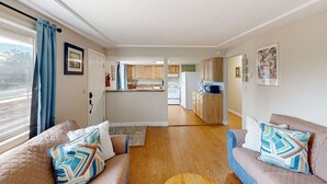 Ein Wohnzimmer mit einer Couch, einem Teppich und Blick zur Küche.