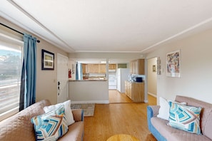 A living room with a sofa, a rug, and a view into the kitchen. - Family-friendly duplex in the Heart of Nye beach, Dog-friendly (Newport)