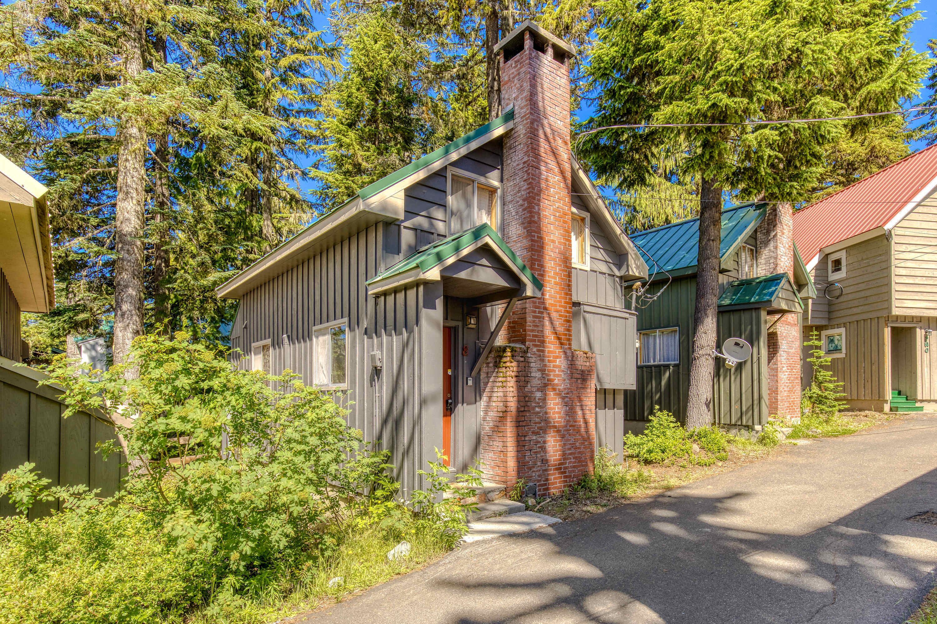 Une maison en bois avec une cheminée en briques, un toit végétalisé et une antenne parabolique.