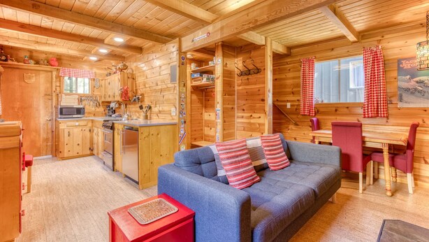 Ein Holzblockhaus-Interieur mit einer Küchenzeile, einer Couch und einem Essbereich.