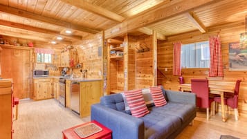 L’intérieur d’une cabane en bois comprend un coin cuisine, un canapé et un espace repas.