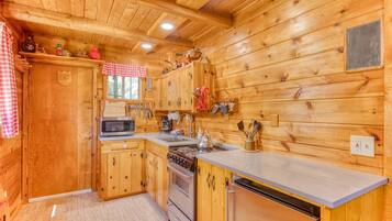 L’intérieur d’une cabane en bois comprend une cuisine équipée de meubles de rangement en bois, d’une cuisinière, d’un four à micro-ondes et d’un évier.