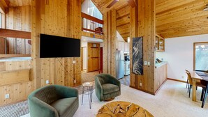 Un intérieur en bois comprenant un téléviseur, un canapé, un fauteuil, une table à manger et un ventilateur de plafond.