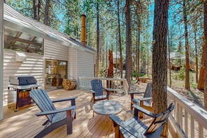 A wooden deck with outdoor furniture, a grill, and a view of the surrounding forest. - Relax and Reconnect - Your Cozy Family Retreat in Sisters, OR (Black Butte Ranch)