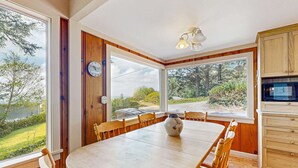 A dining area with a wooden table, chairs, a vase, and a view of the outdoors. - Dog-friendly home & ocean views - near the beach (Manzanita)