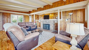 A spacious living room with leather sofas, a stone fireplace, and wooden paneling. - Dog-friendly home & ocean views - near the beach (Manzanita)