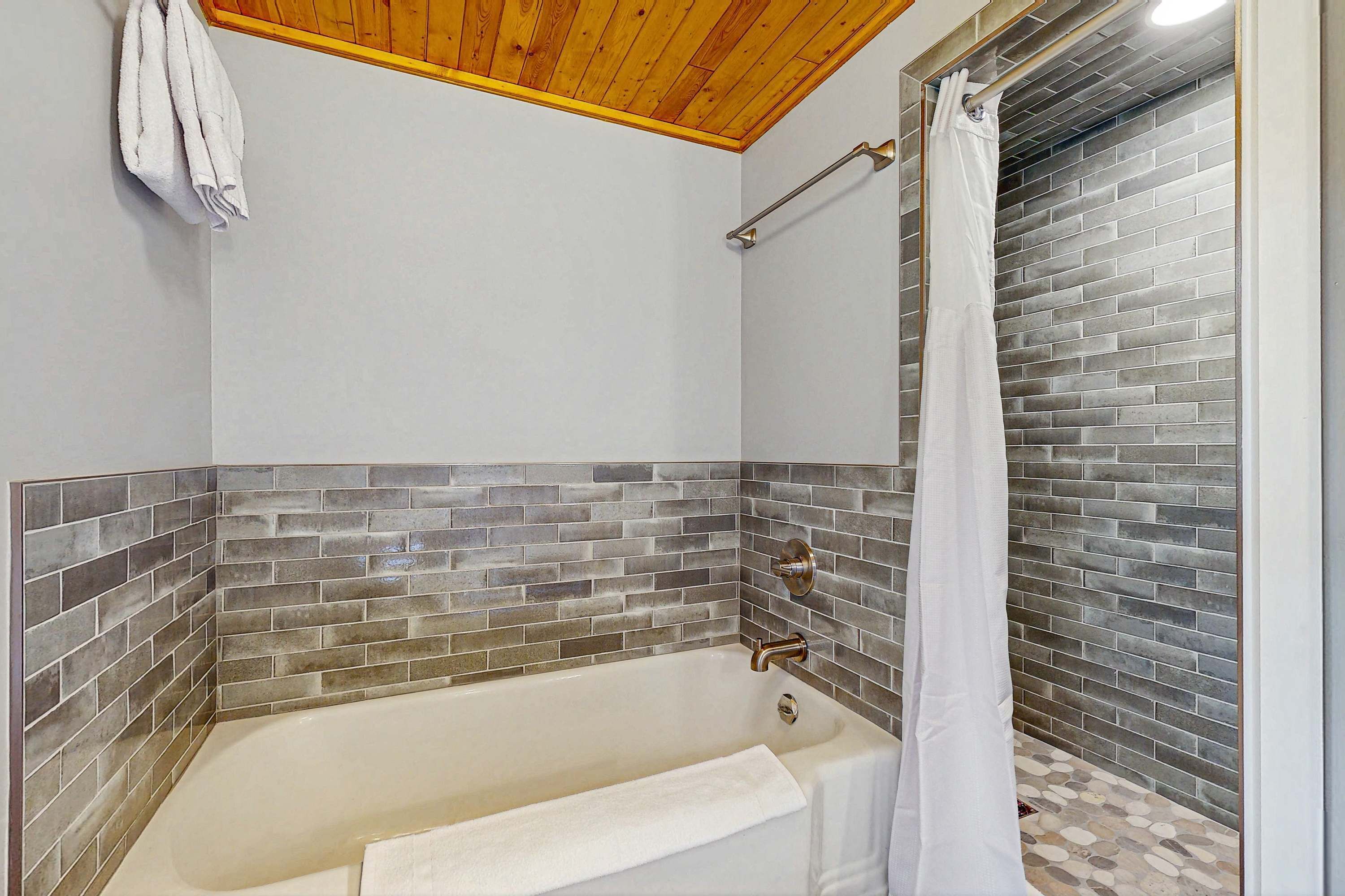 Un bagno con una vasca, una tenda da doccia e un portascopevoli.