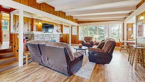 A spacious living area with a fireplace, wooden floors, and a high ceiling. - Dog-friendly home & ocean views - near the beach (Manzanita)