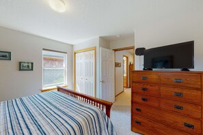 A bedroom with a bed, dresser, TV, and a door leading to another room. - Dog-friendly 2-story duplex with gas fireplace, enclosed yard, gas grill & W/D (Manzanita)