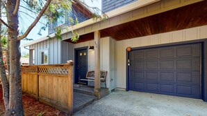 A two-story house with a front porch, a garage, and a wooden fence. - Dog-friendly 2-story duplex with gas fireplace, enclosed yard, gas grill & W/D (Manzanita)