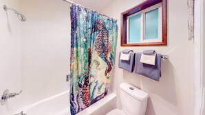 Ein Badezimmer mit Duschvorhang, Toilette und zwei Handtüchern, die auf einem Haken hängen.