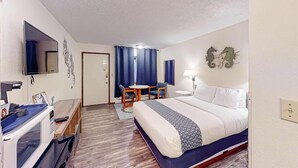 Ein Hotelzimmer mit Bett, Schreibtisch, Stuhl, Fernseher und Mikrowelle.