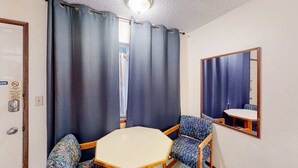 Ein kleiner Raum mit einem einzelnen achteckigen Tisch, zwei stufenförmig gemusterten Stühlen, einem Spiegel und einer Tür mit einem Schild.