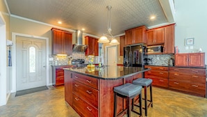 A spacious kitchen with a large island, wooden cabinets, and modern appliances. - Dog-friendly ocean view home with WiFi, remote work spaces, and washer&dryer (Gold Beach)