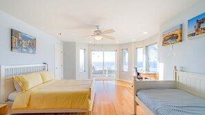 A bedroom with a bed, a desk, and a balcony. - Dog-friendly ocean view home with WiFi, remote work spaces, and washer&dryer (Gold Beach)