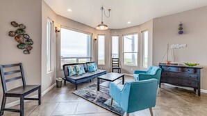 A spacious living room with a sofa, chairs, a coffee table, and a view of the ocean. - Dog-friendly ocean view home with WiFi, remote work spaces, and washer&dryer (Gold Beach)