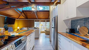 Une cuisine moderne avec des poutres en bois, un grand réfrigérateur et un téléviseur.