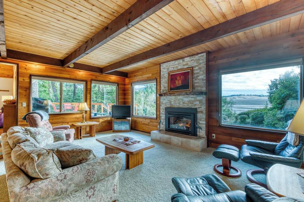 Una sala de estar acogedora con chimenea, asientos cómodos y ventanas amplias con vistas al exterior.