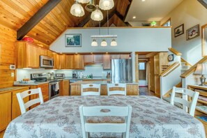 A kitchen with wooden cabinets, a microwave, and a dining area with a table and chairs. - Gorgeous riverfront house with entertainment - near Bay Street and the beach (Florence)