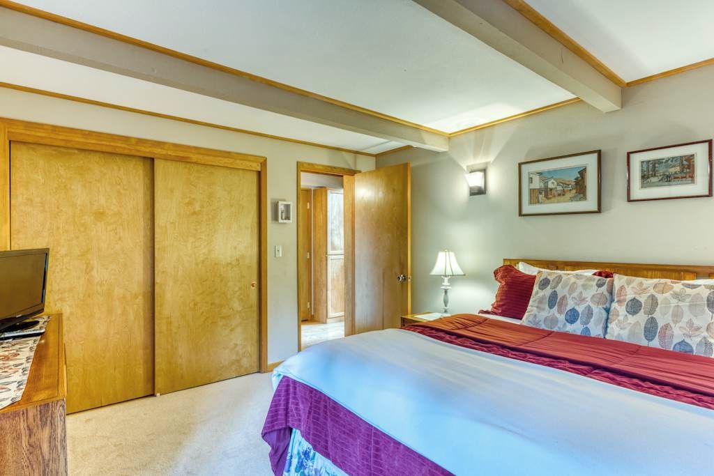A hotel room with a bed, a desk with a laptop, wooden wardrobes, and two framed pictures on the wall.