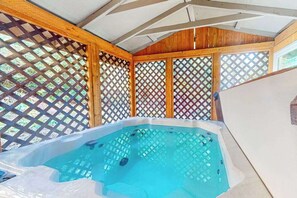 A hot tub with a wooden frame and lattice panels.