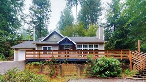 Une maison à deux étages dotée d’une terrasse en bois, d’un porche couvert et d’un escalier menant à l’étage supérieur.