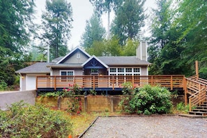 A two-story house with a wooden deck, a covered porch, and a staircase leading to the upper level.