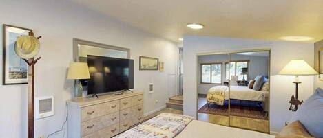 A bedroom with a bed, dresser, television, and a mirror.