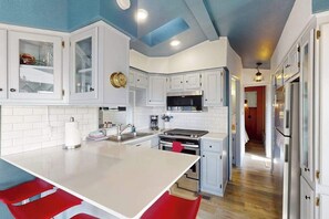 A kitchen with white cabinets, a central island, and red bar stools. - Coastal retreat with ocean views, patio, WiFi, streaming (Brookings)