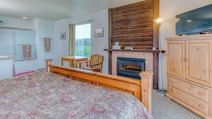 Une chambre à coucher avec un lit, une armoire en bois, une télévision, une cheminée et une fenêtre.