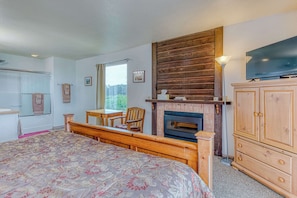 Une chambre à coucher avec un lit, une armoire en bois, une télévision, une cheminée et une fenêtre.
