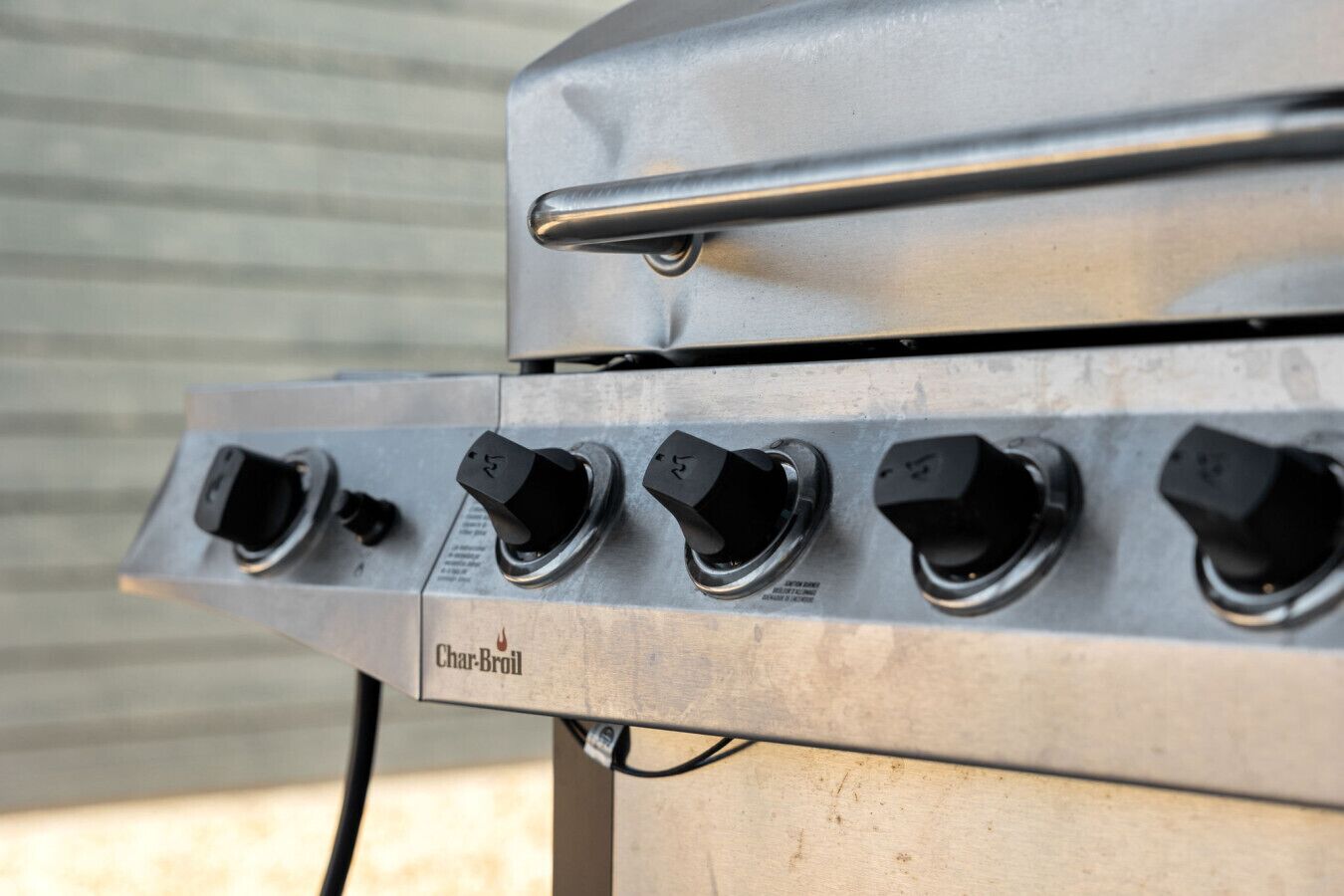A Char-Broil grill with four black knobs and a metal handle.