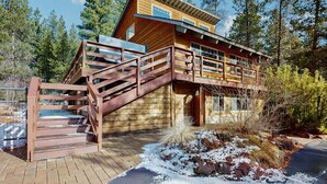 Eine Holzhütte mit einer Treppe, die zu einer Terrasse führt, umgeben von Bäumen.