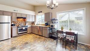 A modern kitchen with a central island, built-in appliances, and a dining area with a view. - Well-stocked and centrally located home with patio & enclosed yard (Eugene)