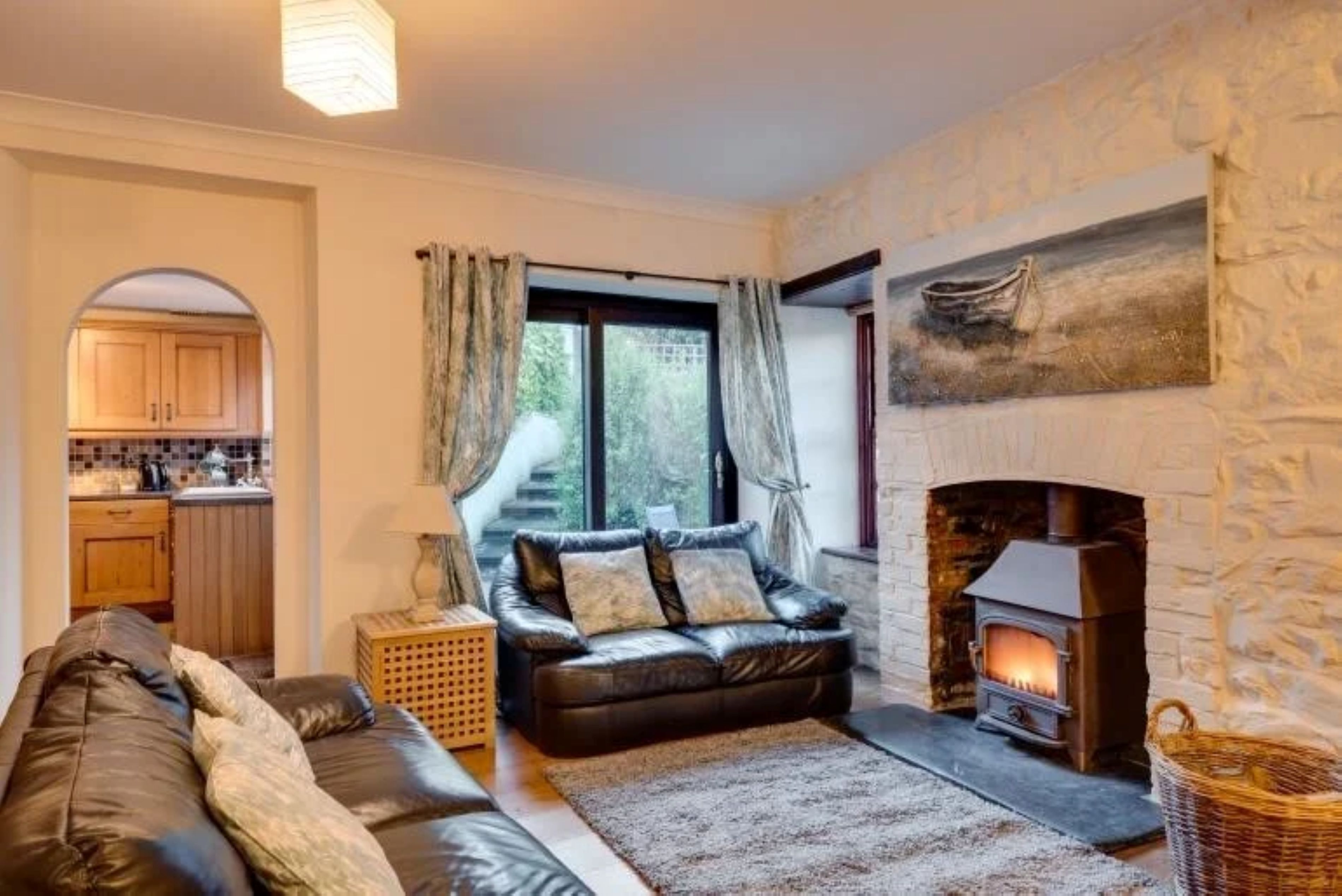 A cozy living room with a fireplace, a sofa, a rug, and a painting on the wall.