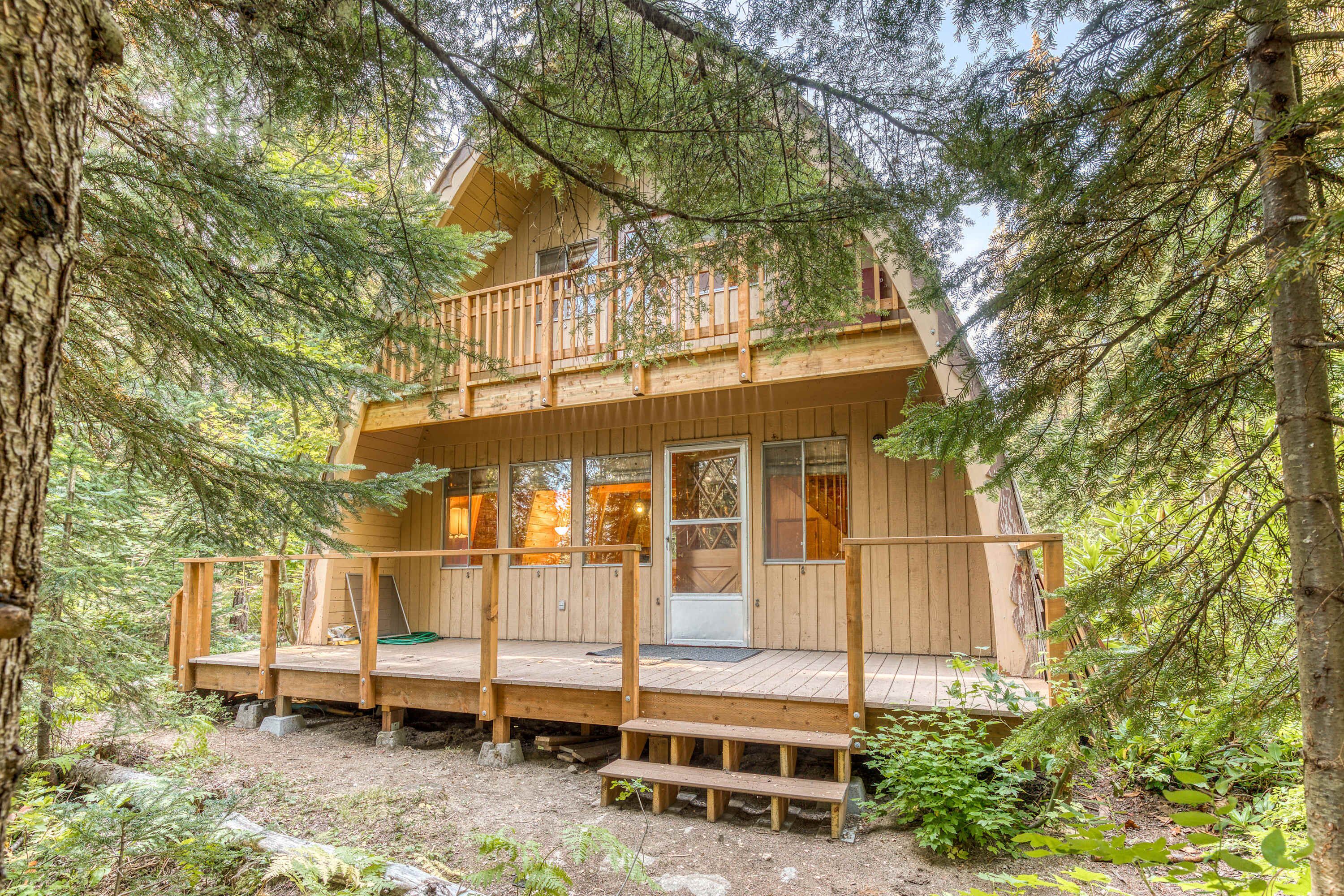 Eine Holzhütte mit einer Holzterrasse, einem Balkon und einer Tür mit Glasfeldern.
