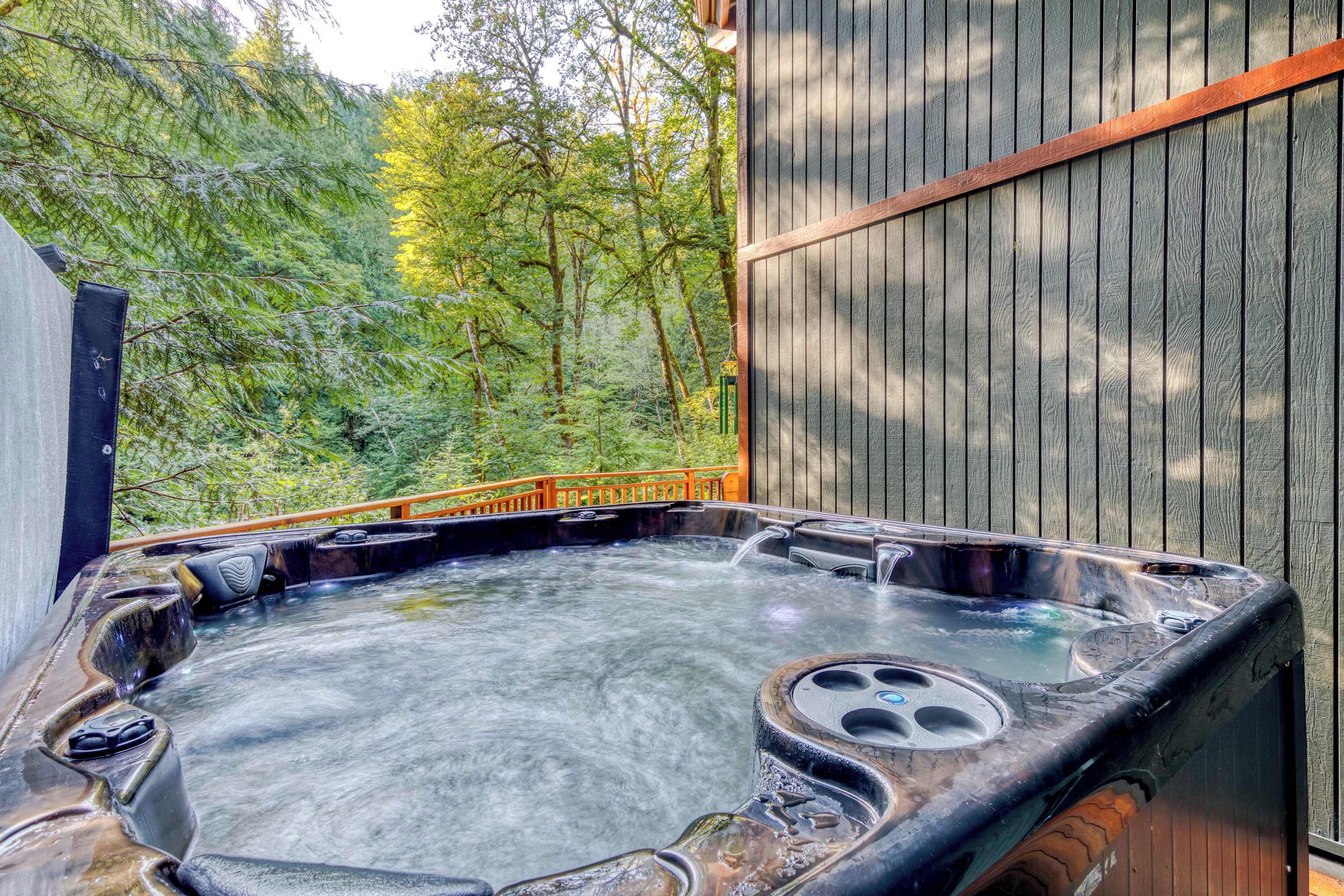 Un bain à remous doté d’une terrasse en bois et entouré d’une clôture en bois, le tout niché au milieu des arbres.
