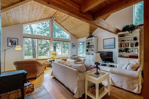 Ein gemütliches Wohnzimmer mit Kamin, großen Fenstern und einer Bücherwand.