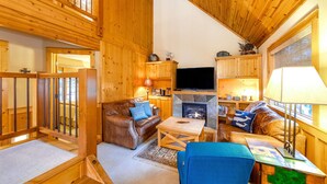 Un intérieur en bois avec une cheminée, un canapé et un téléviseur.