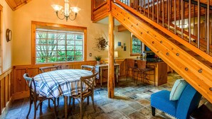 Un escalier en bois, un coin repas avec une table et des chaises, et un canapé bleu.