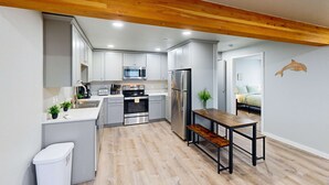 A modern kitchen with grey cabinets, stainless steel appliances, a wooden ceiling, and a dining area with a bench. - Spacious multi-unit coastal getaway, close to the river and downtown, with WiFi (Florence)