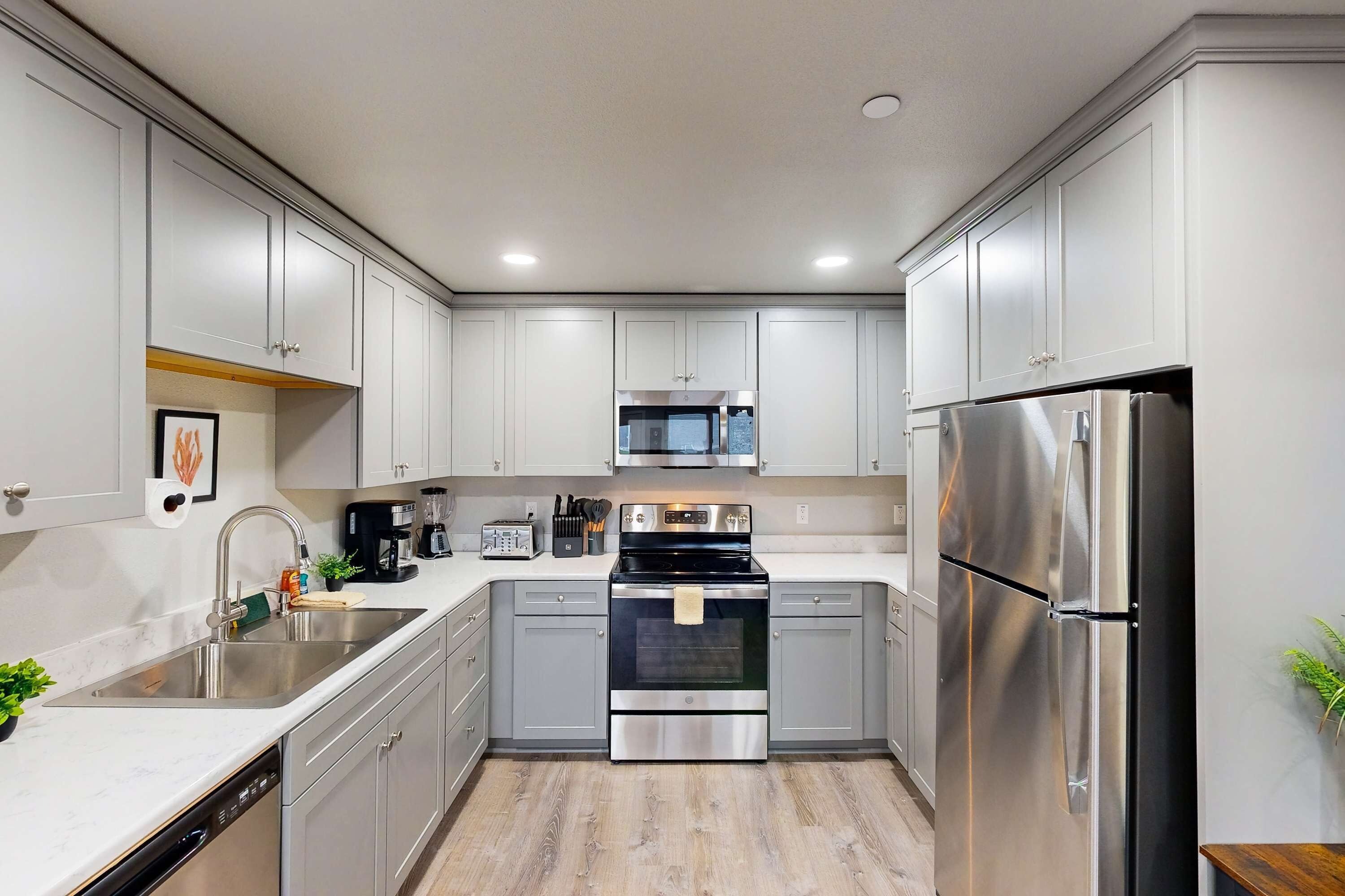 A modern kitchen with stainless steel appliances, grey cabinets, and a dishwasher.