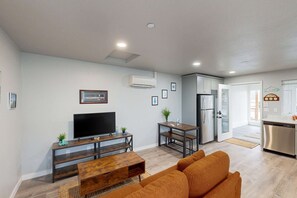 A modern living room with a flat-screen TV, wooden coffee table, and orange sofa. - Spacious multi-unit coastal getaway, close to the river and downtown, with WiFi (Florence)