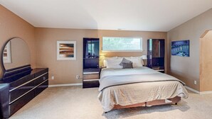 A bedroom with a bed, dresser, and artwork on the walls.