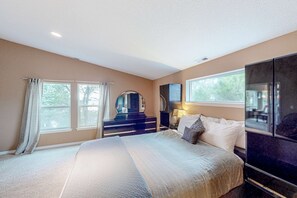 A bedroom with a large bed, a dresser, a mirror, and a TV.